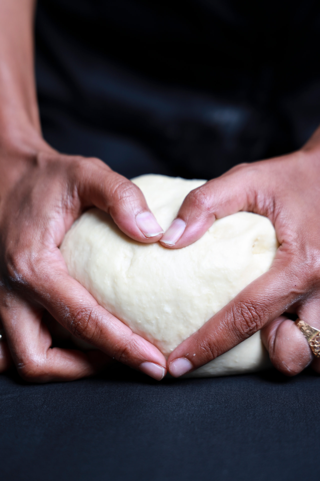 Hands shaping dough into a heart